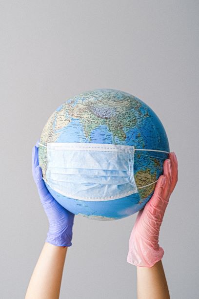 Image of gloved hands holding a globe with mask.